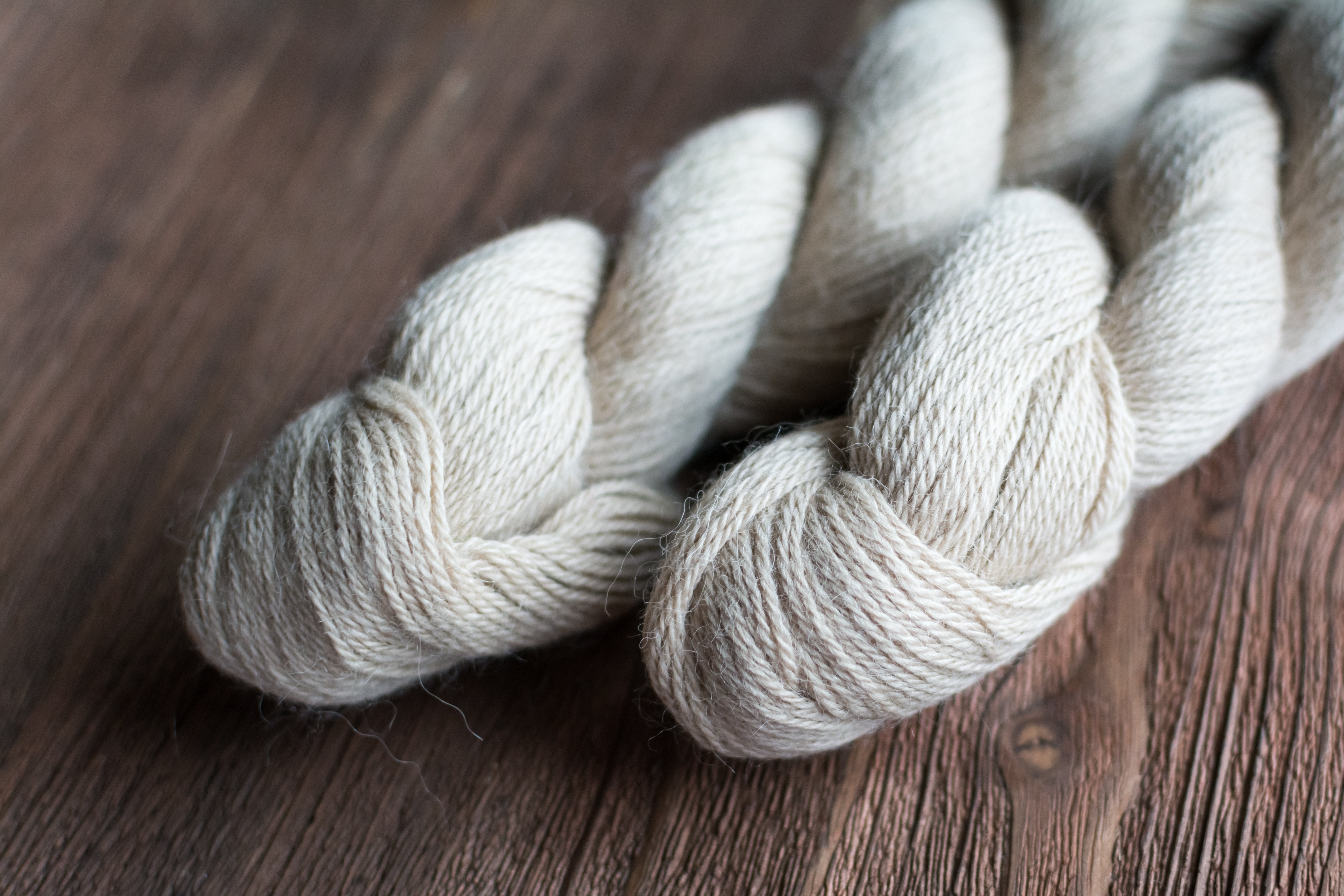 White Dk weight yarn lays nicely atop a dark stained wood table.